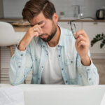 een man wrijft in zijn ogen en heeft hoofdpijn.